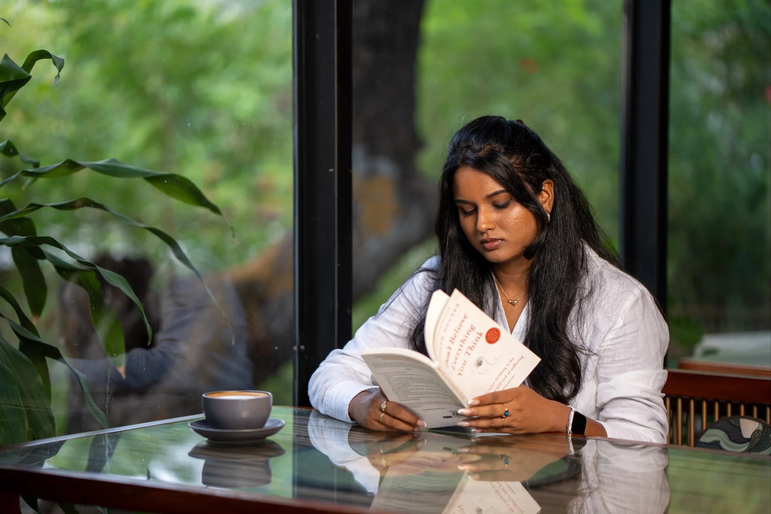 Santhoshini reading at a café table